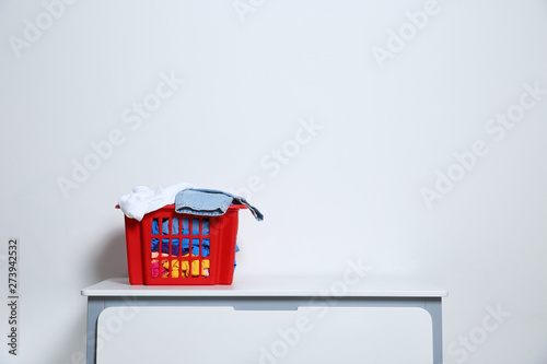 Laundry basket with dirty clothes on cabinet at white wall, space for text