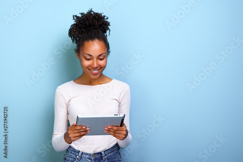 Smiling woman standing with ipad looking at the screen and happily smile