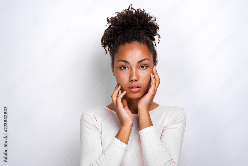Closeup portrait of a beautiful serious girl over light background touches herself face - Image Closeup portrait of a beautiful serious girl over light background touches herself face - Image