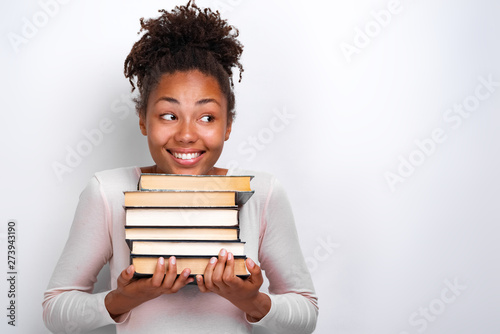 Portrait of happy nerd young girl holding books over white background. Back to school