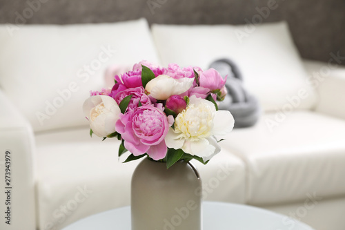 Vase with bouquet of beautiful peonies in room
