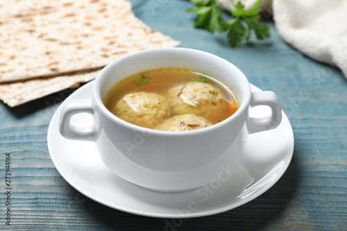 Bowl of Jewish matzoh balls soup on color wooden table