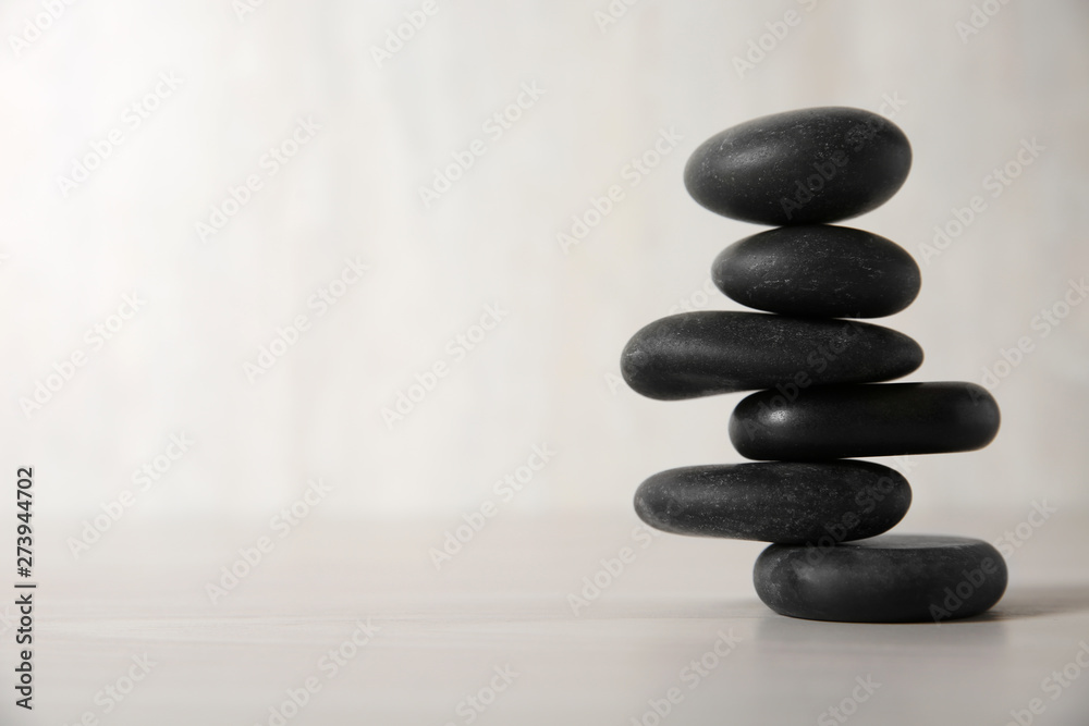 Stack of black spa stones on light background. Space for text Stack of black spa stones on light background. Space for text