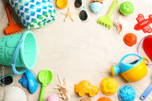 Flat lay composition with colorful beach toys on sand. Space for text