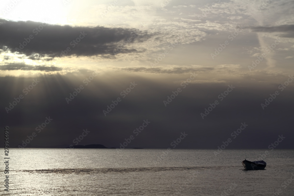 Obraz premium Sunset in the sea with a boat. A picture of a small boat with a beautiful sunset background.