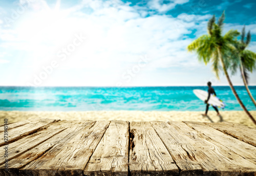 Desk of free space and summer blurred background of beach with surfers 
