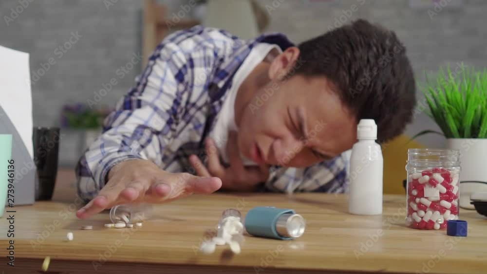young asian man in a shirt asthmatic with attacks of suffocation uses an inhaler slow mo