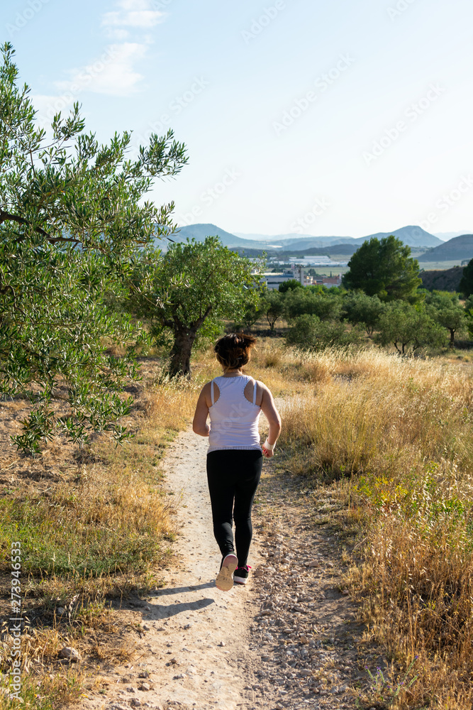 Fit middle-aged woman running through a rural field Fit middle-aged woman running through a rural field