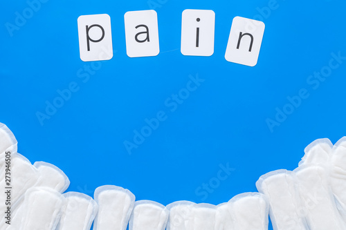 Pain copy for menstrual period concept with sanitary pads on blue background top view space for text