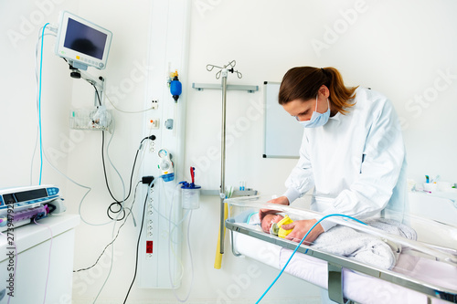 Nurse in ICU examining premature born baby
