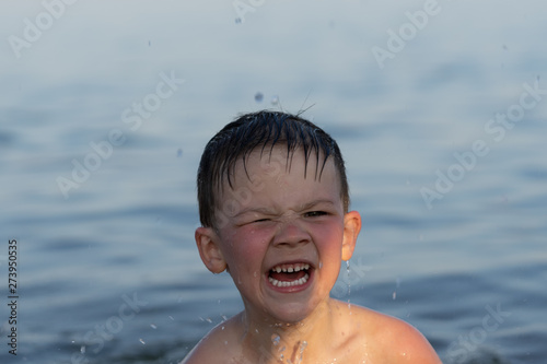 A boy of three years is swimming in the sea at sunset with his brother. © Виктор Кеталь