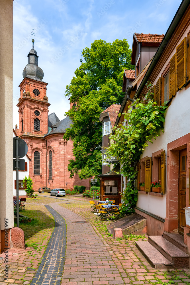 Fototapeta premium Narrow street with view of the church in the old town of Amorbach in Lower Franconia, Bavaria, Germany