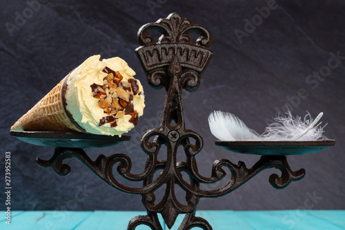 Fotografía close up of ice cream cone and feather on a balanced scale concept of non fat ic