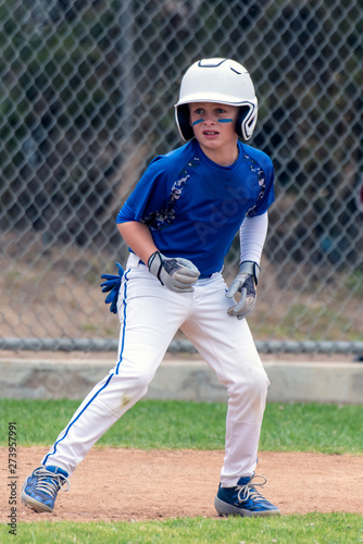 Canvas Print Youth baseball player in blue uniform and white helmet anticipating the right time to run