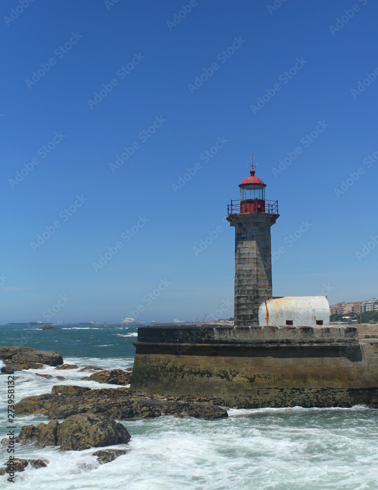 beautiful strict lighthouse on the shore of the blue atlantic ocean in portugal, vertical