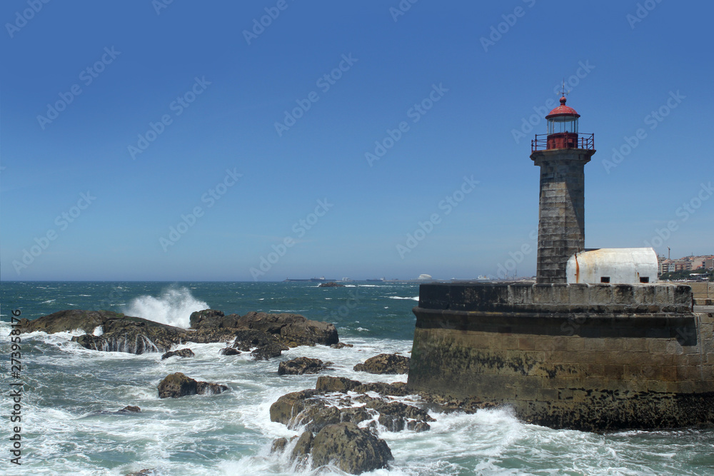 beautiful strict lighthouse on the shore of the blue atlantic ocean in portugal