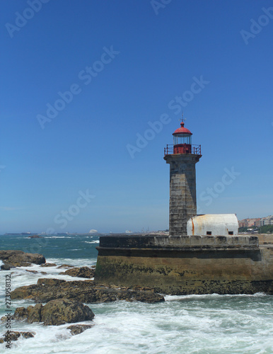beautiful strict lighthouse on the shore of the blue atlantic ocean in portugal, vertical