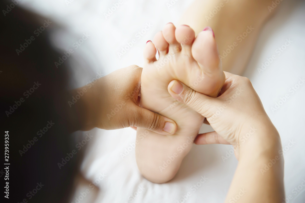 Woman receiving foot massage service from masseuse close up at hand and foot - relax in foot massage therapy service concept Woman receiving foot massage service from masseuse close up at hand and foot - relax in foot massage therapy service concept