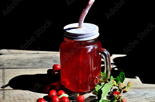Compote of cherry and mulberry on a wooden table, sunny day.