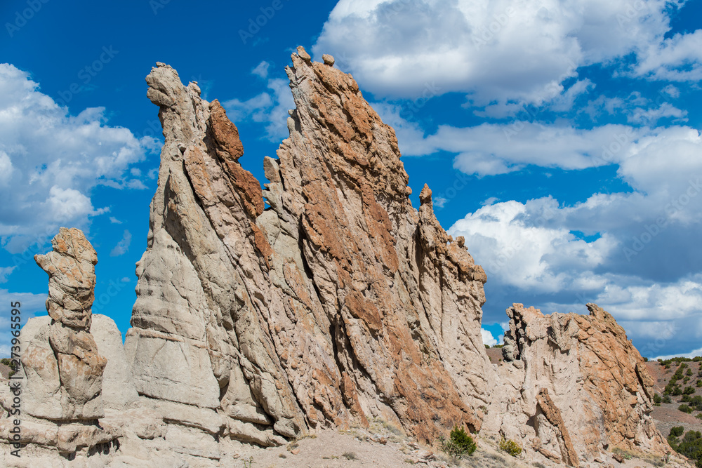 Unusual, craggy rock formations and rugged pinnacles under a beautiful blue sky with white puffy clouds - Plaza Blanca near Abiquiu, New Mexico
