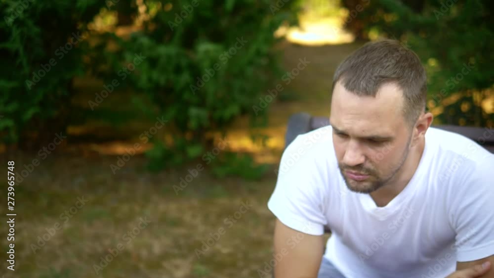 Depressed Sad young man sitting alone on a bench in a summer park. copy space Depressed Sad young man sitting alone on a bench in a summer park. copy space