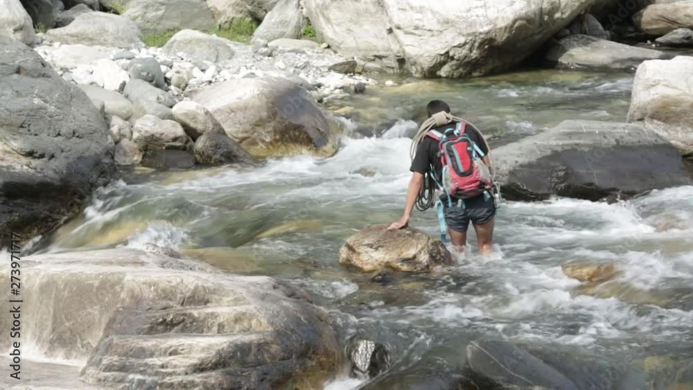 A trainer crossing the flowing mountainous river in the upper Himalayas, Uttarakhand, India. A trainer crossing the flowing mountainous river in the upper Himalayas, Uttarakhand, India.