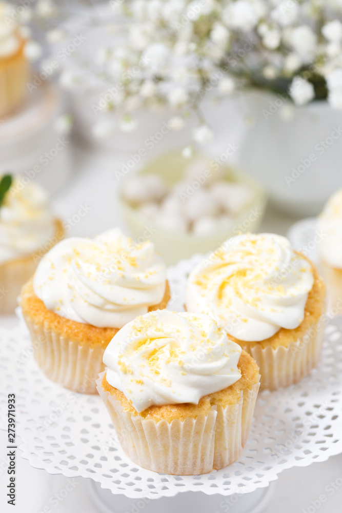 Vanilla cupcakes with cream cheese frosting on a white cake stand