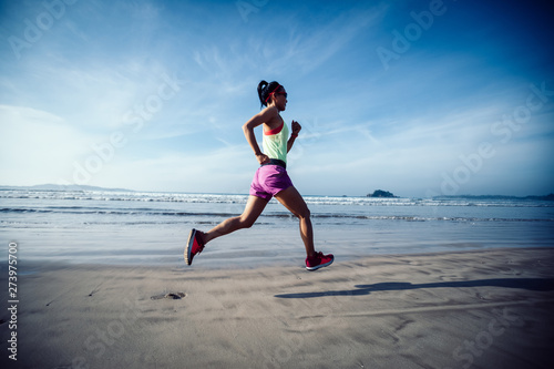 Fitness woman runner running on beach