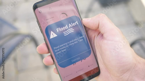 Receiving a FLOOD warning notification on a smartphone screen. Blinking alert concept