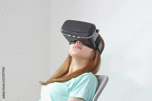 Young woman wearing virtual reality glasses at home.
