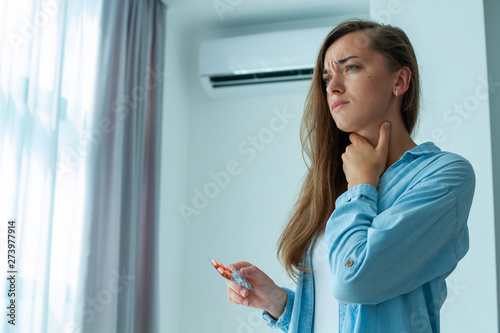 Sad upset woman caught a cold from the air conditioner and suffering from sore throat photo