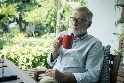 senior man happiness sitting and holding cup of coffee at balcony near garden at nursing home for relaxing
