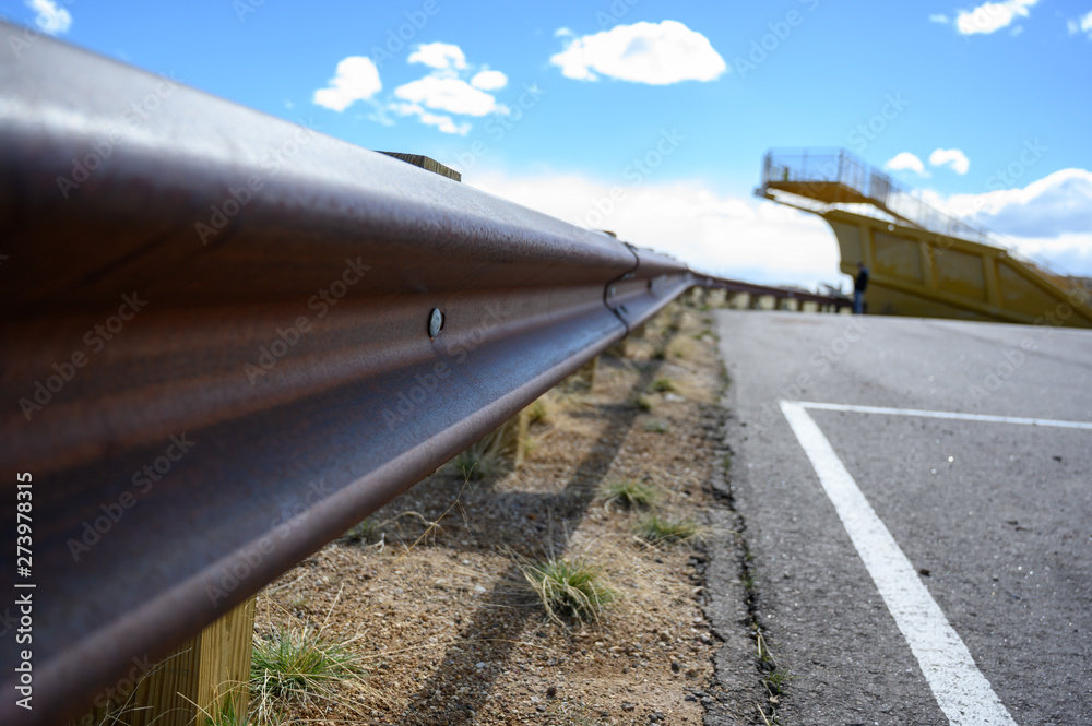 closeup of rusted metal guardrail along paved roadway closeup of rusted metal guardrail along paved roadway
