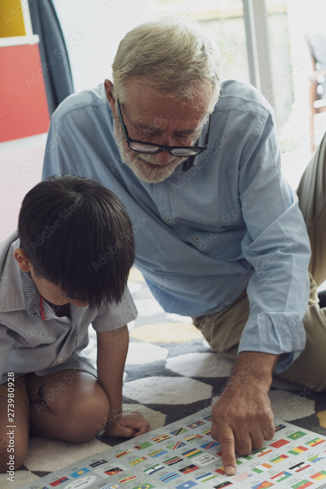 Fototapeta premium senior man happiness, smiling nurse and grandson are sitting on the floor and playing games at living room together