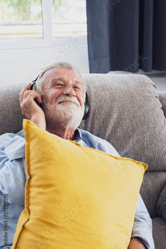 senior man happiness sitting on the sofa and listening music with headphone at living room for relaxing