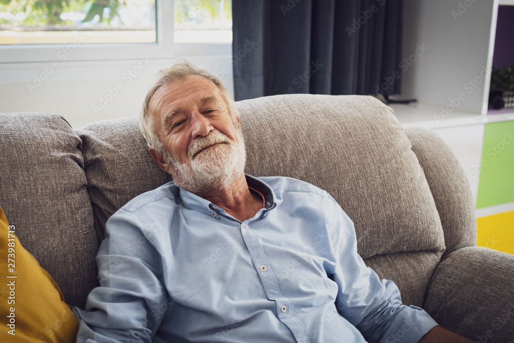 senior man happiness sitting on the sofa and smiling and thumbs up or point at living room for relaxing senior man happiness sitting on the sofa and smiling and thumbs up or point at living room for relaxing