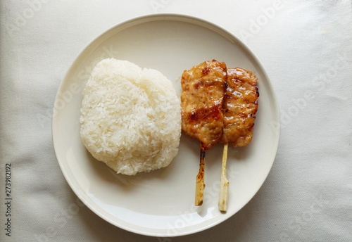 Thai food style, Top view of grilled pork on skewer with sticky rice on white plate isolated on white background, ready for eat or serve photo
