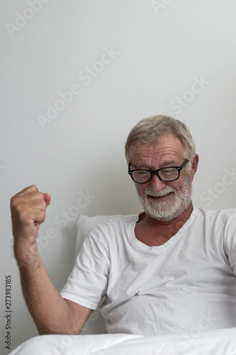 senior man with smiling and cheer on bed at white room