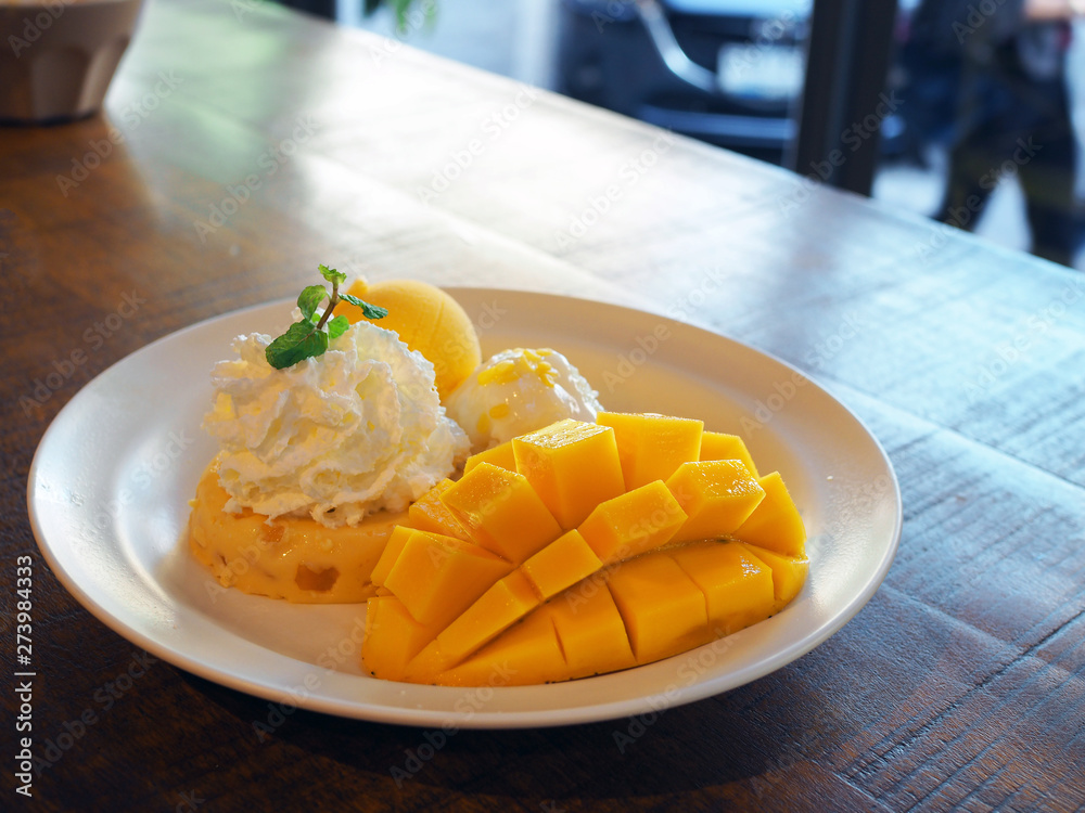 Beautiful tasty ripe mango with ice cream, pudding and sticky rice on a white plate.