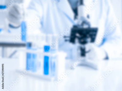 Fototapeta Naklejka Na Ścianę i Meble -  Scientist research and show blue chemical tubes with microscope in laboratory blur background for graphic resource