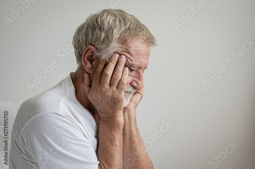 senior man thinking or try to remember alone on bed in white room
