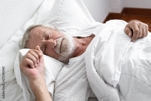 senior man sleeping alone and headache or dreaming nightmare on bed in room