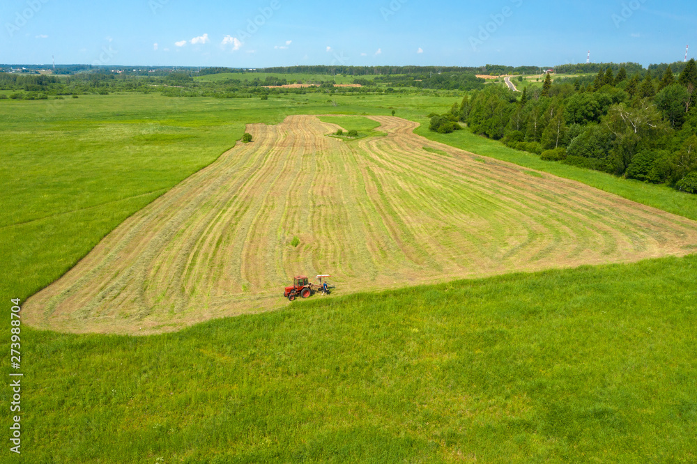 Naklejka premium Aerial view on the countryside and the tractor mows the grass