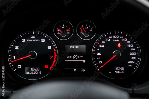 Interior view of car with black salon. Modern luxury prestige car interior: speedometer, dashboard and tachometer with white backlight and other buttons. Soft focus