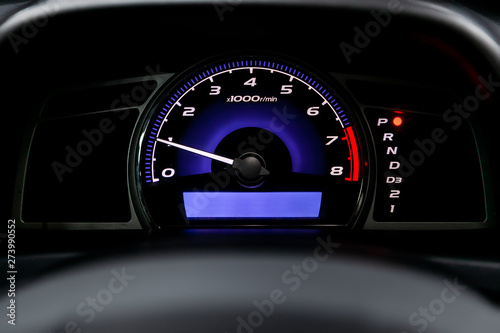 Interior view of car with black salon. Modern luxury prestige car interior: speedometer, dashboard and tachometer with white backlight and other buttons. Soft focus