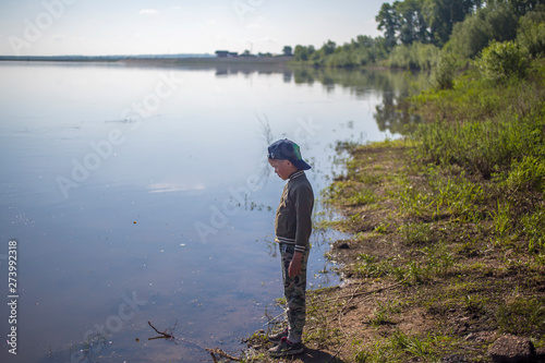 a boy stands on the bank of the river