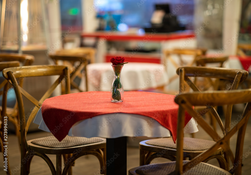 Close up of the centerpiece of a spanish restaurant table with red checkered tablecloth and wood chairs