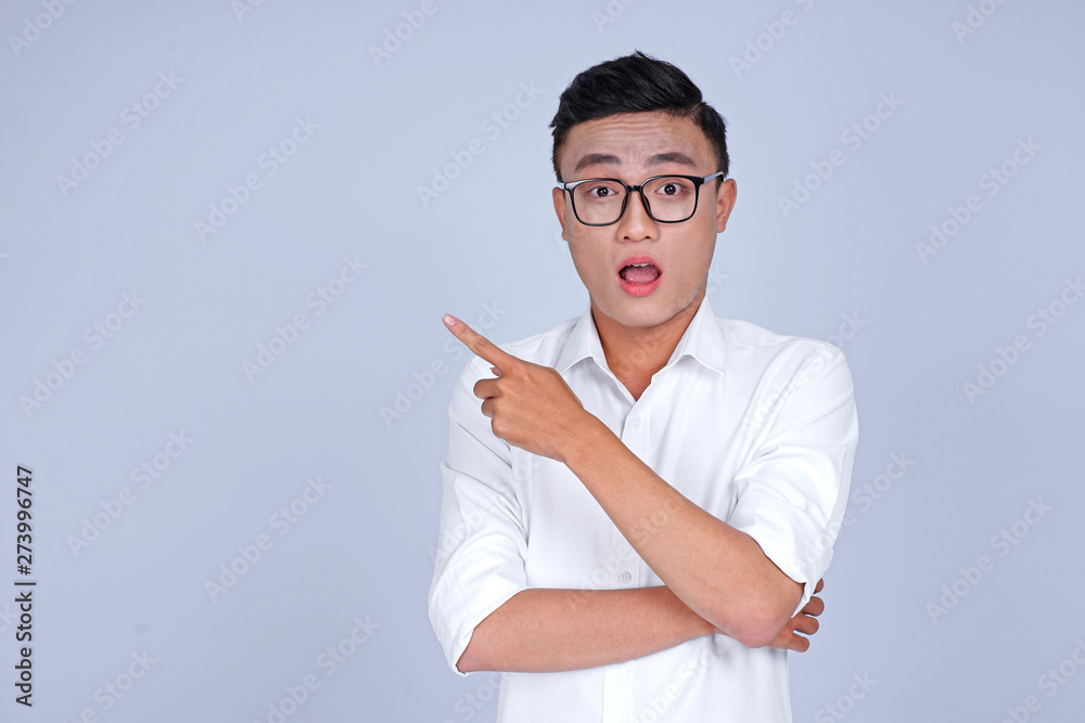Asian young handsome attractive man with hand showing pointing message on blank background Asian young handsome attractive man with hand showing pointing message on blank background
