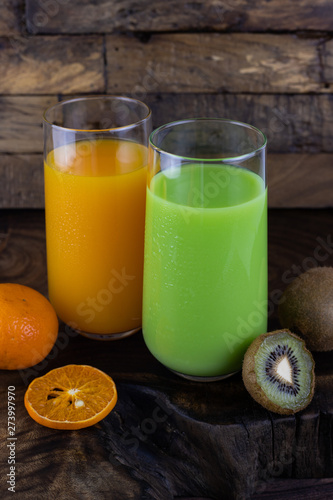 Fresh healthy orange, kiwi juice, smoothie in a glass on wooden background. summer concept.