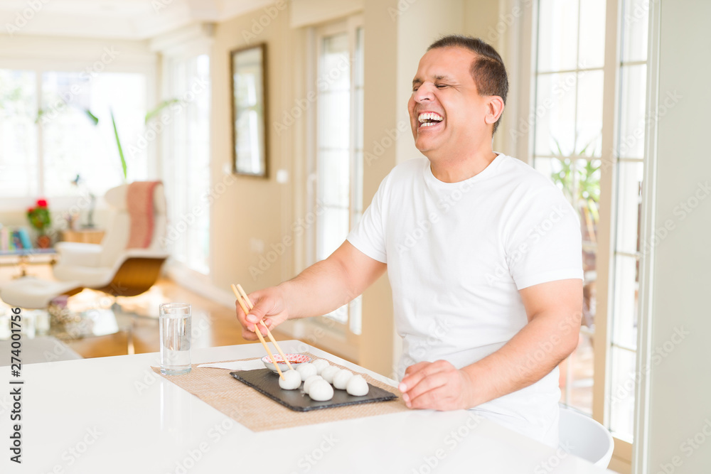Middle age man eating asian dim sum using chopsticks at home Middle age man eating asian dim sum using chopsticks at home